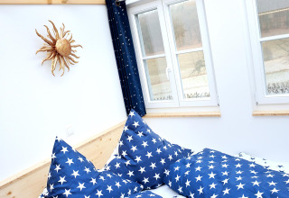 Interieur van glampingaccommodatie met blauwe sterrenbeddengoed, glazen dak en ramen bij Zur Grünen Kutte.