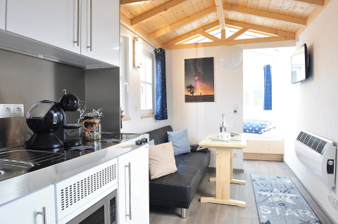 Binnenzicht van glamping accommodatie 'Zur Grünen Kutte - Zigeunerwagen Thüringen' met keuken en zithoek.