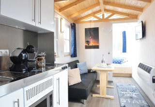 Interior view of glamping accommodation 'Zur Grünen Kutte - Zigeunerwagen Thüringen' with kitchen and seating area.