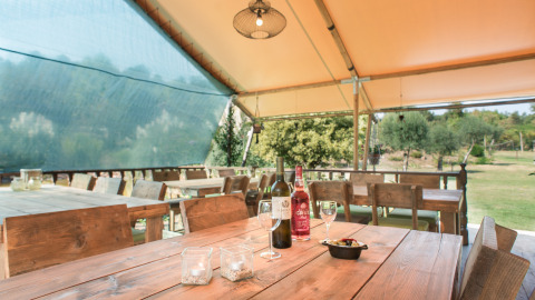 Udendørs spiseområde under telt på Quinta do Cascalhal - Safaritenten Braga med vinflasker på bordet.