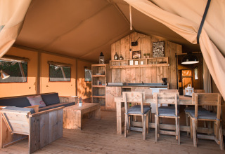 Rustic glamping tent interior at Quinta do Cascalhal - Safaritenten Braga with wooden furniture and warm light.