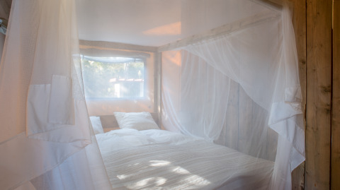 Lit confortable avec moustiquaire dans un hébergement glamping à Quinta do Cascalhal - Safaritenten Braga, Portugal.