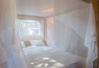 Schlafbereich mit Moskitonetz in Glamping-Unterkunft bei Quinta do Cascalhal - Safaritenten Braga, Portugal.
