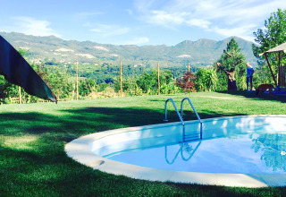View of the pool, lawn, and mountains at Quinta do Cascalhal - Safaritenten Braga, luxury glamping site.