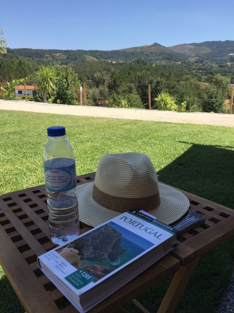 Vista su Quinta do Cascalhal - Safaritenten Braga con cappello, bottiglia d'acqua e guida di viaggio Portogallo.