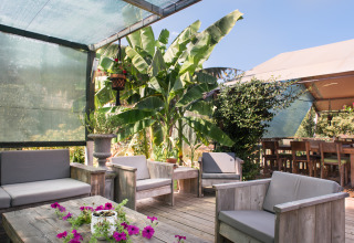 Lounge all'aperto a Quinta do Cascalhal - Safaritenten Braga con mobili in legno e piante verdi rigogliose.