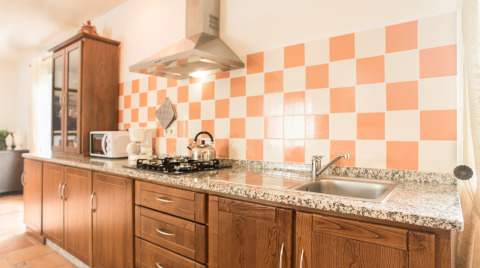Kitchen area in Quinta do Cascalhal - Safaritenten Braga with wood cabinets, gas stove and checkered tiles.