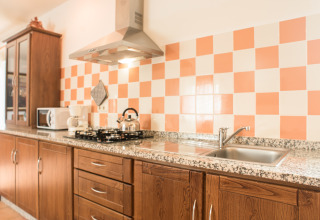 Keuken bij Quinta do Cascalhal - Safaritenten Braga met houten kasten, gasfornuis en geblokte tegels.