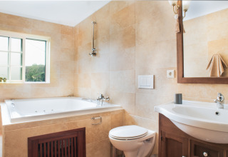 Helles Badezimmer in Quinta do Cascalhal - Safaritenten Braga mit Badewanne, WC und Spiegel.