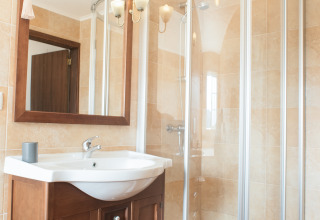 Badezimmer mit Dusche, Waschbecken und Holzmöbeln bei Quinta do Cascalhal - Safaritenten Braga Glamping.