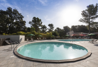 Außenpool mit Liegestühlen und Sonnenschirmen bei Huttopia Fontvieille – Glamping Provence in Frankreich.