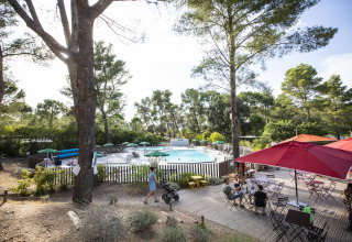 Piscine extérieure entourée de terrasses et arbres à Huttopia Fontvieille – Glamping Provence camping.