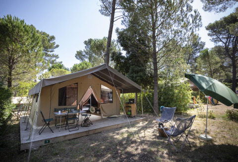 Hébergement glamping à Huttopia Fontvieille – Glamping Provence avec terrasse, chaises et arbres autour.