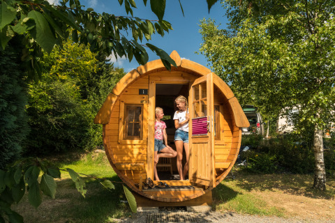 Two people enjoy glamping in wine barrel accommodation at Camping im Bergischen Land, surrounded by nature.