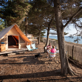 Glamping accommodatie bij Huttopia Noirmoutier - Glamping Vendée met tent en stel genietend van het zeezicht.