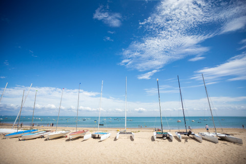 Veleros alineados en la arena frente al mar y el cielo azul en Huttopia Noirmoutier - Glamping Vendée.