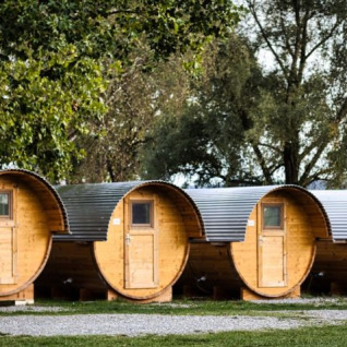 Row of round wooden sleeping barrels at Camping Markelfingen - Schlaffässer by Lake Constance, Germany.