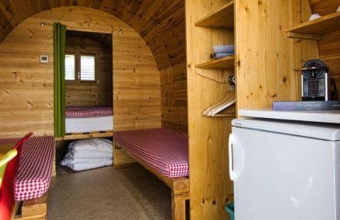 Vista interna di una sistemazione glamping al Camping Markelfingen sul Lago di Costanza con letti e frigo.
