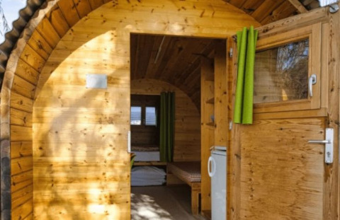 Wooden glamping pod at Camping Markelfingen - Schlaffässer near Lake Constance with green curtains.