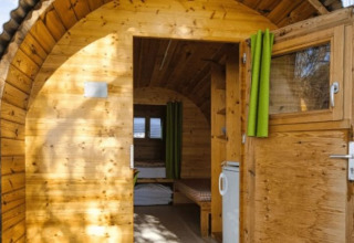 Schlaffass Glamping-Unterkunft bei Camping Markelfingen am Bodensee mit Holzwänden und grünen Vorhängen.