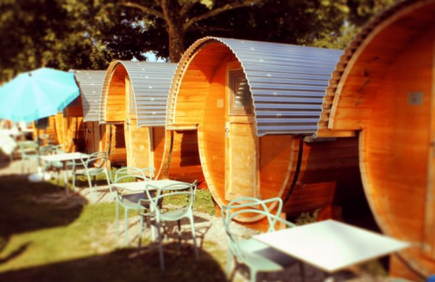 Rij houten slaapvaten met metalen dak en buitenzitjes bij Camping Markelfingen aan het Bodenmeer.