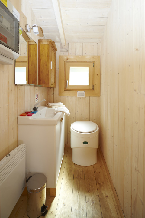 Baño de madera con inodoro y lavabo en alojamiento glamping Baumpalast Boomhutten en Baden-Württemberg.