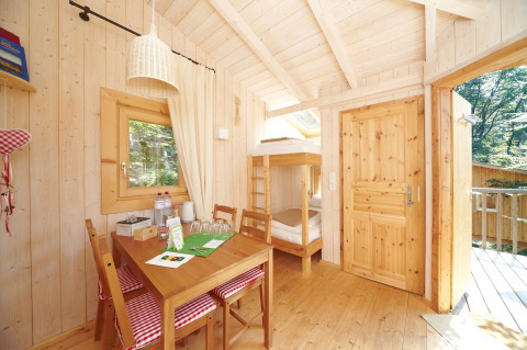 Intérieur lumineux et chaleureux d'une cabane en bois avec lits superposés au Baumpalast Boomhutten, Baden-Württemberg.