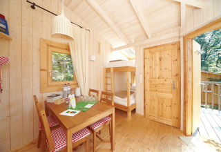Bright, cozy wooden cabin with bunk beds and dining table at Baumpalast Boomhutten glamping in Baden-Württemberg.