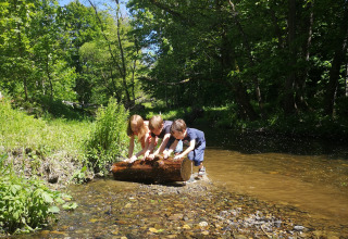 Bambini giocano presso un ruscello immersi nella natura, Camping de Marcourt, Lussemburgo belga.