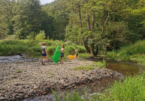 Bambini che giocano vicino a un ruscello al Camping de Marcourt - Tipitenten nel Lussemburgo belga, tra alberi.