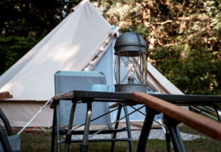 Glampingplads med telt og udendørs bord, lanterne og stole på Camping de Marcourt i Belgisk Luxembourg.