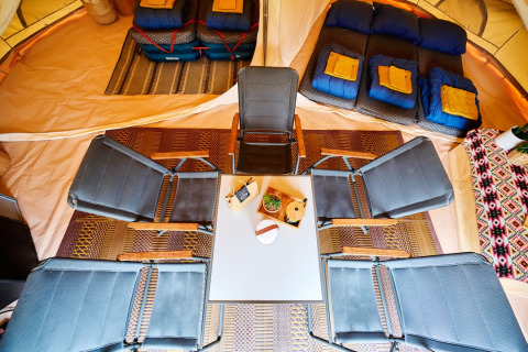 Indvendig billede af glamping i Camping de Marcourt i Belgisk Luxemburg med senge, stole og bord.