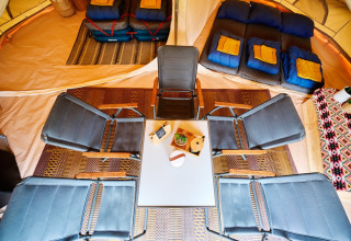 Vista interna del glamping presso Camping de Marcourt in Lussemburgo Belga con letti, sedie e tavolo.