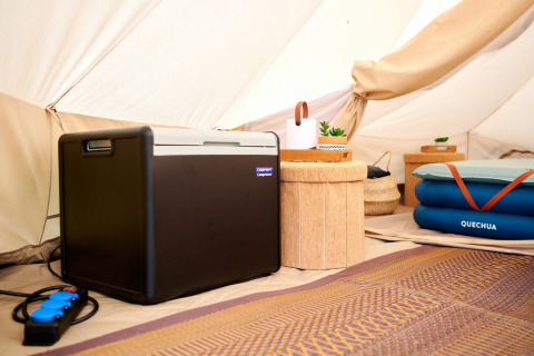 Indretning i glamping-telt på Camping de Marcourt med køleboks, madras og komfortable faciliteter.