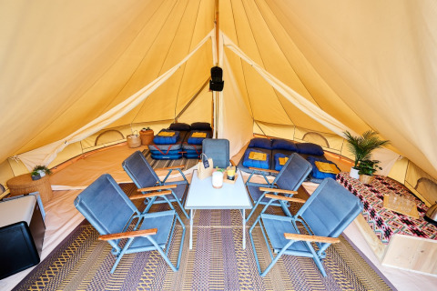 Interieur van een luxe tipitent met comfortabele bedden en stoelen op Camping de Marcourt in Belgisch Luxemburg.