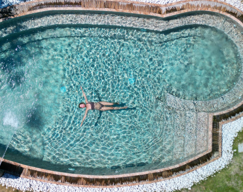 Frau entspannt im Pool bei Procida Camp & Resort - Luxe airstreams Glamping-Anlage, sonniger Tag.