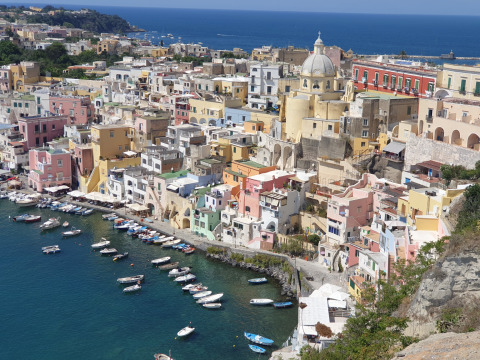 Udsigt over Procida i Italien med farverige huse, både i havnen og Procida Camp & Resort - Luxe airstreams.