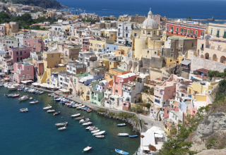 Blick auf Procida, Italien mit bunten Häusern, Hafen und Procida Camp & Resort - Luxe airstreams.