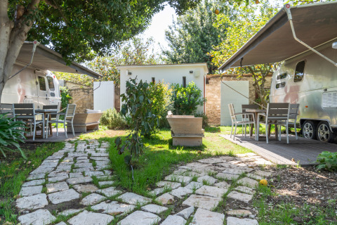Glamping accommodation at PROCIDA Camp & Resort with luxury airstreams, garden and outdoor seating area.
