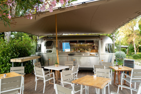 Schicker Essbereich im Freien mit Retro-Wohnwagen und Sitzplätzen bei PROCIDA Camp & Resort.