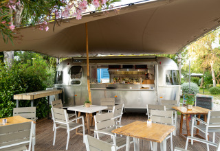 Luxe buitenrestaurant met zilveren airstream caravan bij PROCIDA Camp & Resort, comfortabele glamping.