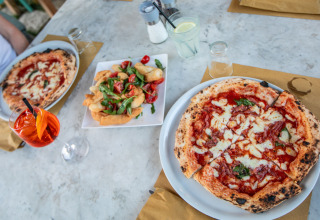 Twee Napolitaanse pizza’s en een bordje hapjes op een tafel bij PROCIDA Camp & Resort - Luxe airstreams.