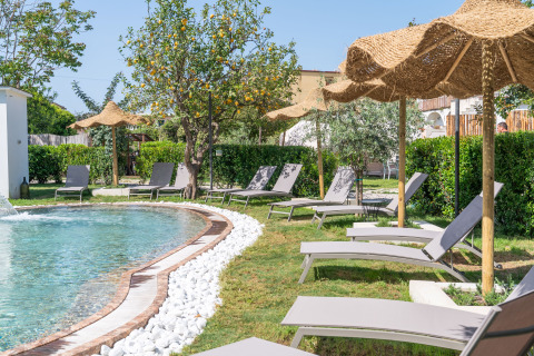 Area piscina all’aperto con lettini e ombrelloni di paglia al PROCIDA Camp & Resort - Luxe airstreams, glamping.