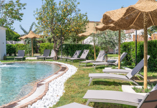 Espace piscine extérieure avec transats et parasols en paille au PROCIDA Camp & Resort - Luxe airstreams, glamping.