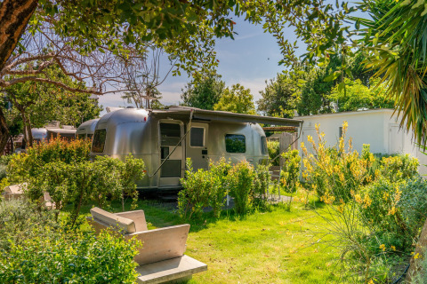 Glamping accommodatie PROCIDA Camp & Resort: luxe airstreams in een zonnige, groene tuinomgeving.