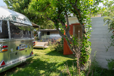 Luxuriöse Glamping-Unterkunft bei PROCIDA Camp & Resort mit Airstreams in einem grünen Garten.