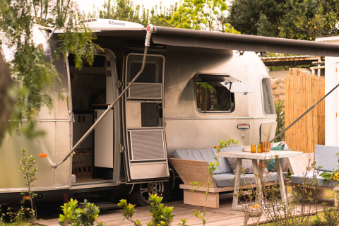 Airstream glamping accommodation at Procida Camp & Resort with outdoor seating area and awning shade.
