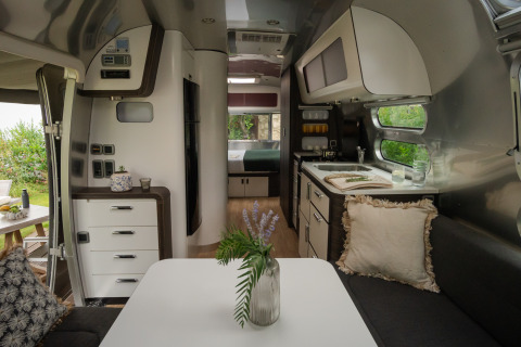 Binnenzicht van een luxe airstream bij PROCIDA Camp & Resort met moderne keuken en gezellige zithoek.