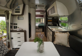 Vista interna di un lussuoso airstream glamping al PROCIDA Camp & Resort con cucina moderna e area salotto.