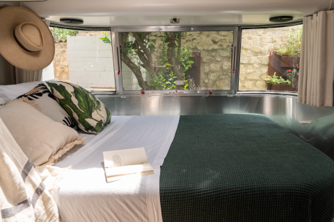 Interior view of a luxurious airstream trailer with cozy bed at PROCIDA Camp & Resort glamping site.